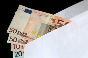 Euro bills in white envelope on the black background. Income, bonus or bribe concept