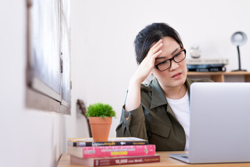 Modern young Asian woman working from home with sad and unhappy.