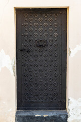 Vintage armored black iron door of ancient house in an old city.