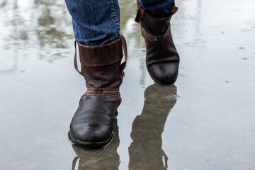 Leather boots on a wet sidewalk in the rain. Close up.