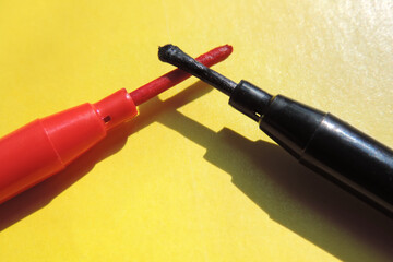   two markers red and black opposite each other  on a yellow background, long rods   