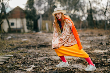 Obraz premium Funny and unusual girl in a long yellow skirt, white jacket and orange scarf rejoices