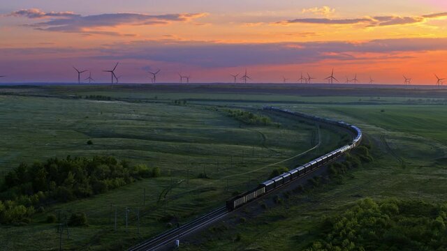 Train, railway in the meadow, windmills in the distance, sunset sky, aerial view