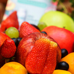 Set of berries and fruits in wooden box. Apple, strawberry, grape, berry and peach on a red brick...