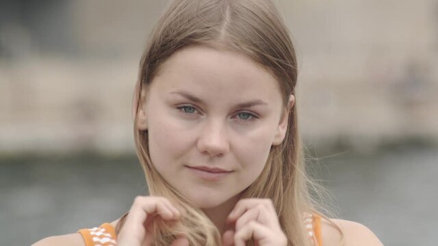 Portrait of a Pretty Scandinavian Brunette Girl Looking into Camera Smiling and Adjusting her Hair.
