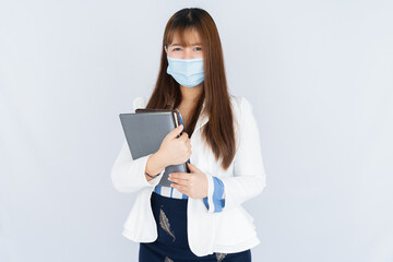 Smiling Asian business woman holding the notebook and looking at the camera over grey background. Back to the normal concept.