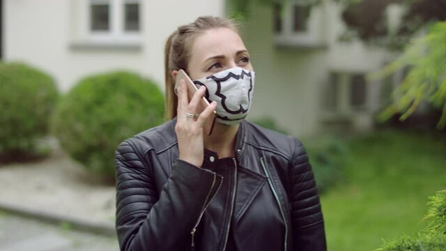 Young woman in the mask is talking on the phone.