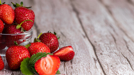 fresh strawberries with flowers and leaves on  wooden background with copy space