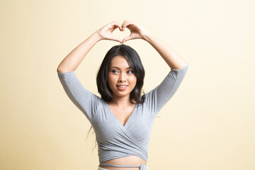 Fototapeta premium Young Asian woman gesturing heart hand sign.