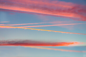 Saturated colorful contrails in salmon sunset sky. 