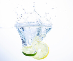 Slice of Lemon and Lime Splashing into Water with a White Background