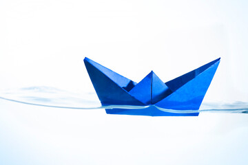 Blue Paper Boat Floating on the Surface of the Water with a White Background