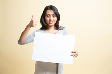 Fototapeta premium Young Asian woman show thumbs up with white blank sign.