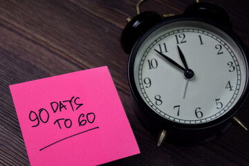 90 Days To Go write on sticky note isolated on wooden table.