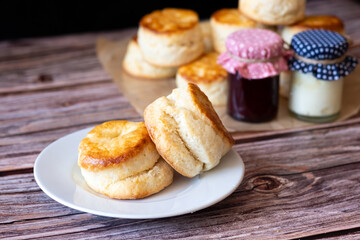 Traditional British Scones on white plate and Cream cheese, Cranberry jam in glass bottle on wooden table background.