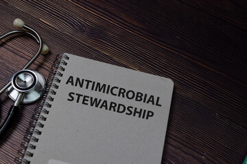 Book about (AMS) Antimicrobial Stewardship isolated on wooden table.