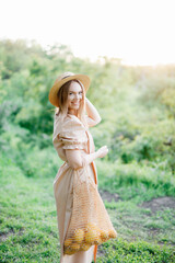 Obraz premium a young girl in a long linen dress, a summer photo shoot, a girl in the forest, a hairstyle with a bow, a string bag with lemons, a girl with a bag and lemons