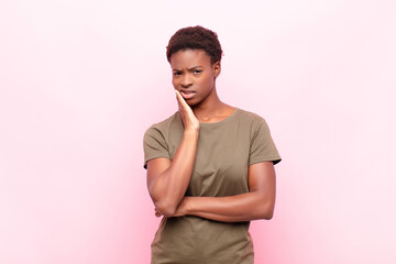 young pretty black womanholding cheek and suffering painful toothache, feeling ill, miserable and...