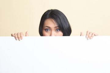 Fototapeta premium Close up of young Asian woman behind a blank sign.
