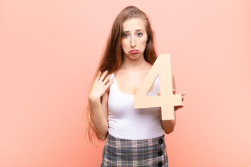 yound blonde woman sad, depressed, unhappy, holding a number 4.