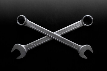 Two wrenches or spanners crossed on black backgorund for concept design. Repair service. Service concept. Pirate sign, motorcycle repair, bikers concept.