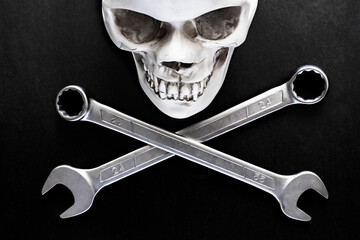 Two crossed wrenches or spanners and skull on black backgorund for concept design. Repair service....