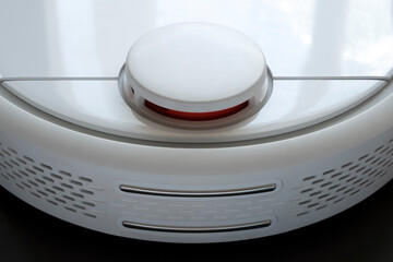 Modern white robot vacuum cleaner isolated on black background. Technology concept. Smart home...