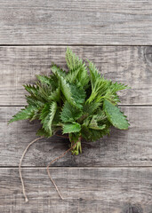 Nettle on rustic boards with copy space. Young nettle bouquet, stinging nettles, urtica. Minimal nature concept. Flat lay.