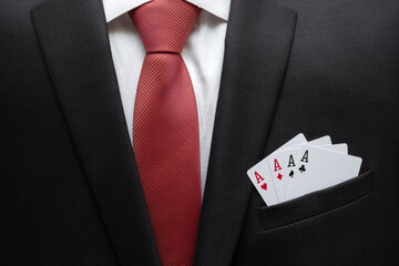 Business man in suit with aces in the pocket of his jacket.  Metaphor to confidence in winning. Businessman ready for risk and development. Self-assurance concept.