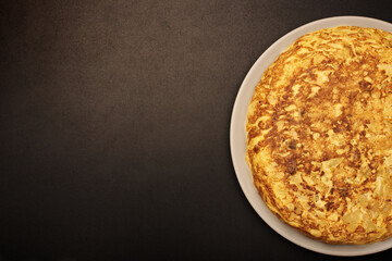 Spanish omelette on a black background. Cooked with eggs, potatoes and onions. Typical spanish food.