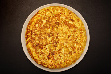 Spanish omelette on a black background. Cooked with eggs, potatoes and onions. Typical spanish food.