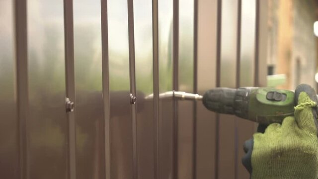 Male Hands Fix The Fence With Special Screws And Screwdriver