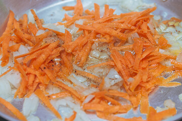 chopped onions and carrots in a frying pan.