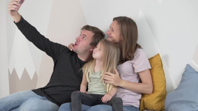 Happy family take a Funny photo, Slow-motion family selfie. A man holds a smartphone in his hand 