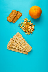 diet bread, orange and granola on a blue background.