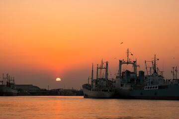 Silhouette many ships mooring on riverside against sunset sky background in evening time