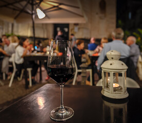 A glass of wine with a candle in an evening street restaurant
