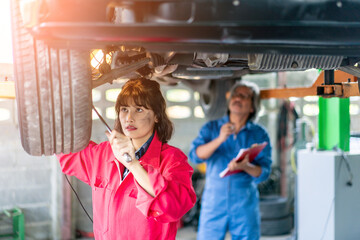 Senior Man and Woman Mechanic Examining Under the Car at the Repair Garage.