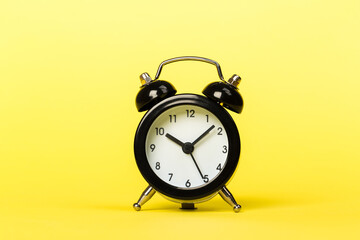black retro alarm clock on a yellow background,