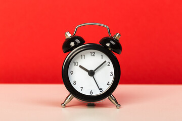 Black retro alarm clock with bells on a wooden table, daily routine concept.