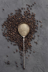Black peppercorn and powder in a metal spoon. Composition of black pepper spice on a dark...