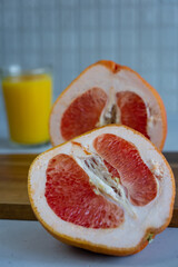 Two halves of grapefruit are laying on wooden cutting board at kitchen