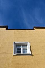 One window on a yellow building against a blue sky