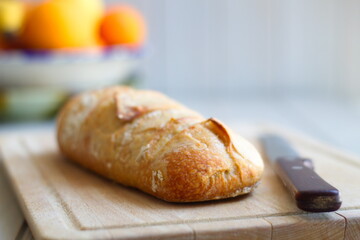 freshly baked rustic loaves of bread on wooden board and with a knife