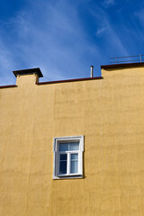 One window on a yellow building against a blue sky