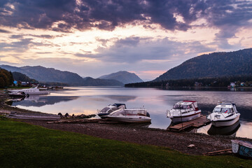 Lake shore with moored motor boats at dawn. Teletskoye Lake, Artybash Village, Altai Republic, Russia