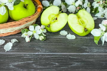 fresh green apples. green apples in a basket and halves of green apples on the table close-up. fresh apples and apple blossoms.