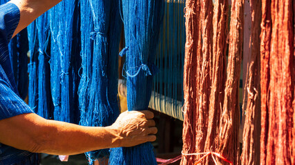 Crafts and craftsmanship. Traditional Isan Thai Cotton indigo weaving. The hand holding the indigo dyeing cloth And natural dyes or bark. Thailand. Selective focus.