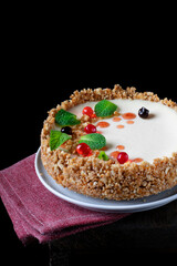 Cheesecake with cream cheese and citrus zest topped with mint, chocolate and jelly balls against the black background