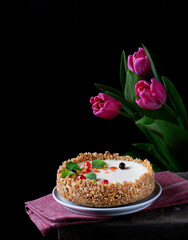 Cheesecake with cream cheese and citrus zest topped with mint, chocolate and jelly balls against the black background